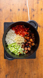 Jambalaya - Ajouter les oignons, le céleri, le poivron et l'ail aux viandes.
