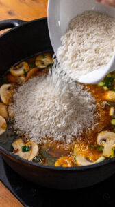 Jambalaya - Ajouter le riz et le mélanger au bouillon pour qu'il soit bien immergé.