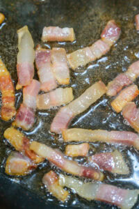 Joues de porc braisées - Faire revenir les lardons dans une sauteuse avec le filet d'huile, juste pour faire fondre leur gras, sans les laisser colorer.