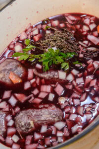 Joues de porc braisées - Verser la marinade par-dessus, avec toute sa garniture aromatique.
