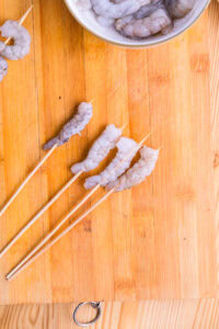 Kushikatsu - Étirer la crevette et la piquer sur la brochette en partant de la queue.