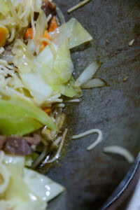 Lo mein - Pousser les nouilles sur un côté du wok.