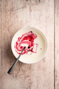 Colorant rouge délayé dans le babeurre à la cuillère dans un bol