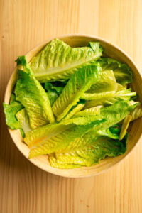 Salade César - Rouler de nouveau les feuilles plutôt que les remuer, jusqu'à ce que l'œuf et les autres ingrédients forment une sauce crémeuse qui nappe les feuilles.