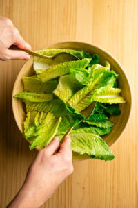 Salade César - Rouler les feuilles avec la fourchette et la cuillère, en les retournant doucement sur elles-mêmes, jusqu'à ce qu'elles soient bien enrobées d'huile.