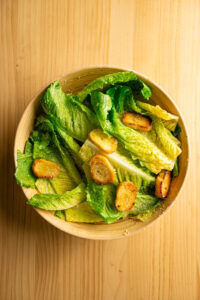 Salade César - Remuer pour enrober les croûtons de sauce et faire adhérer le fromage aux feuilles.