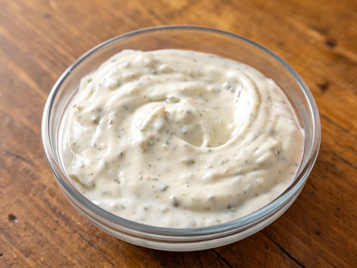Sauce ranch maison dans un bol en verre, mouchetée de persil séché