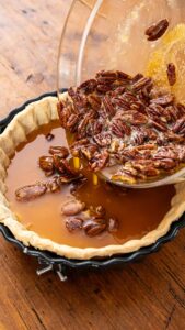 Garniture aux noix de pécan versée dans le fond de tarte précuit