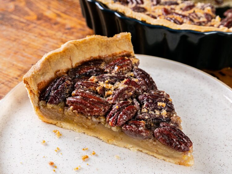 Part de tarte aux noix de pécan sur une assiette, la garniture ambrée sous la couche de noix de pécan brillantes