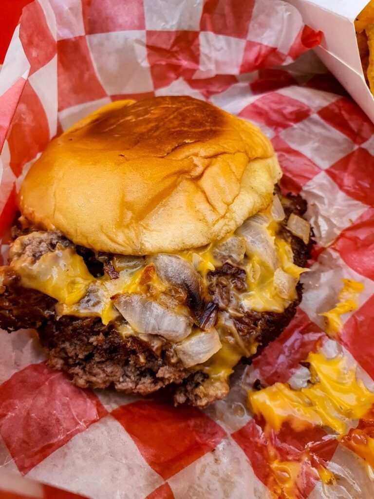 Cheeseburger aux oignons grillés et fromage américain fondu sur papier à carreaux, burger joint, New York